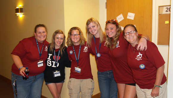 A group of female delegates from the 2012 Kansas YLF link arms and smile for a photo outside of their dorm.